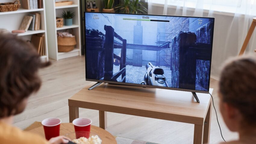 Dzieci grają w gry na telewizorze w salonie.