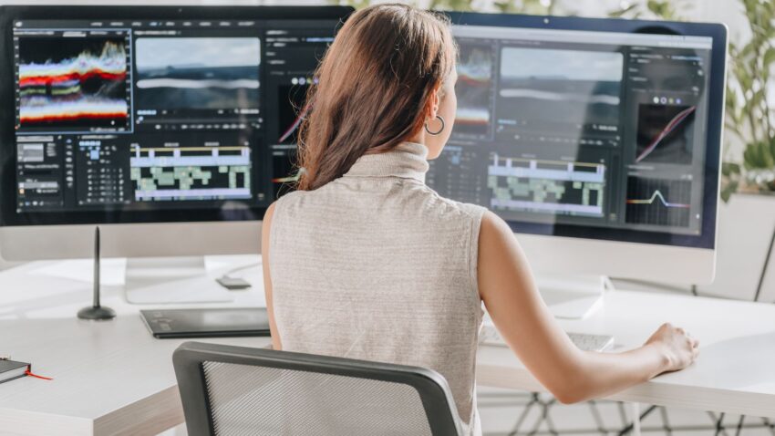 Kobieta pracuje w biurze przy dwóch monitorach.
