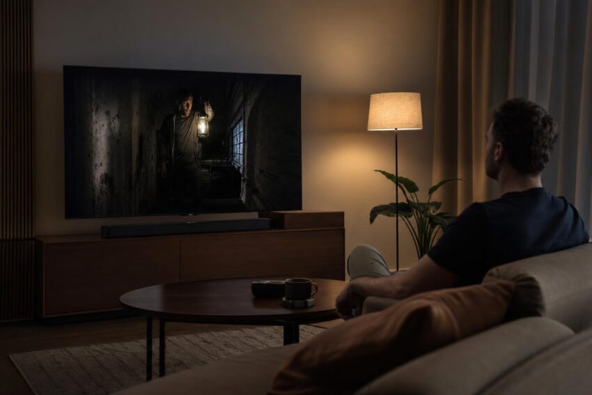 Osoba ogląda ciemny obraz HDR na telewizorze wieczorem w nowoczesnym salonie.